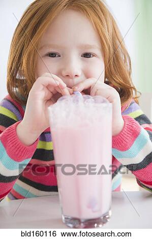 Stock Photograph - Caucasian girl blowing bubbles in strawberry milk. Fotosearch