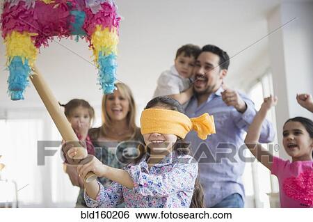 Stock Photograph - Caucasian girl hitting pinata at birthday party. Fotosearch
