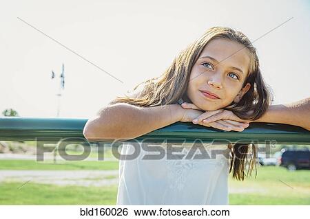 Stock Photograph - Caucasian girl leaning on farm fence. Fotosearch
