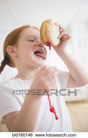 Stock Photograph - Caucasian girl licking messy jelly donut. Fotosearch