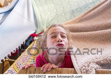 Stock Image - Caucasian girl playing in blanket fort. Fotosearch