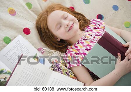 Stock Photo - Caucasian girl reading books on bed. Fotosearch