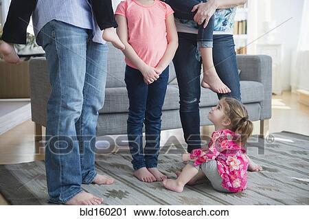 Stock Image - Caucasian girl sitting under family in living room. Fotosearch