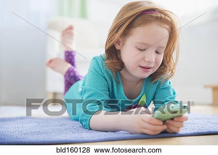 Stock Photo - Caucasian girl using cell phone on floor. Fotosearch