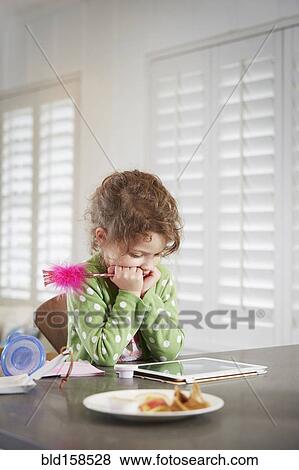 Caucasian girl using digital tablet at table View Large Photo Image Stock Photo - Caucasian girl using digital tablet at table. Fotosearch