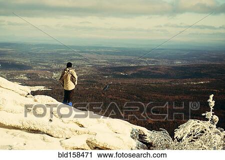 Stock Image - Caucasian hiker admiring scenic view on snowy mountaintop. Fotosearch