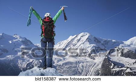 Stock Photo - Caucasian hiker cheering on mountaintop, Monte Rosa, Alps, Italy. Fotosearch
