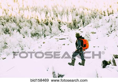 Stock Photo - Caucasian hiker climbing snowy rock formations. Fotosearch
