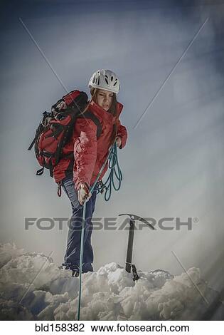 Stock Image - Caucasian hiker pulling rope on snowy mountaintop. Fotosearch
