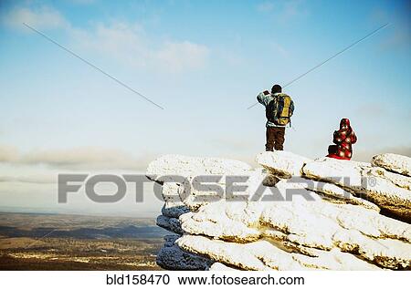 Stock Image - Caucasian hikers admiring scenic view from mountaintop. Fotosearch