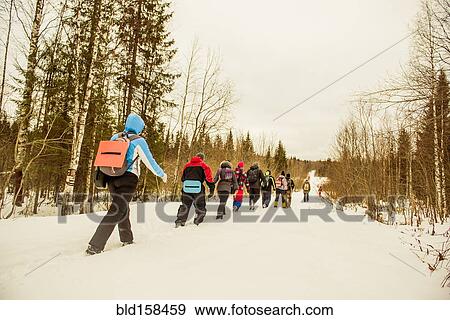 Stock Photo - Caucasian hikers walking in a row on snowy path. Fotosearch