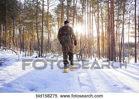 Stock Photography - Caucasian man cross country skiing in snowy forest. Fotosearch
