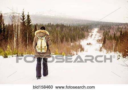 Stock Image - Caucasian man hiking on snowy path. Fotosearch