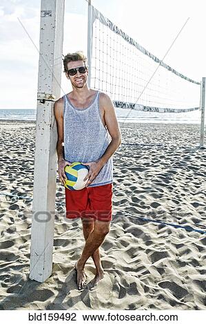 Caucasian man holding volleyball on beach View Large Photo Image Stock Image - Caucasian man holding volleyball on beach. Fotosearch