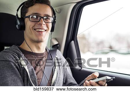 Stock Photo - Caucasian man listening to mp3 player in car. Fotosearch