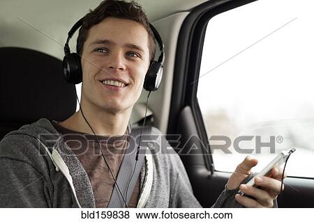 Caucasian man listening to mp3 player in car View Large Photo Image Stock Photo - Caucasian man listening to mp3 player in car. Fotosearch