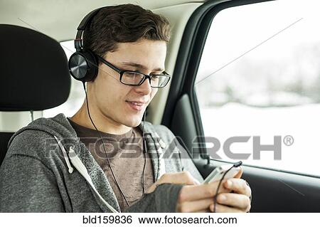 Stock Photograph - Caucasian man listening to mp3 player in car. Fotosearch
