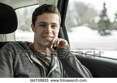 Stock Image - Caucasian man sitting in back seat of car. Fotosearch