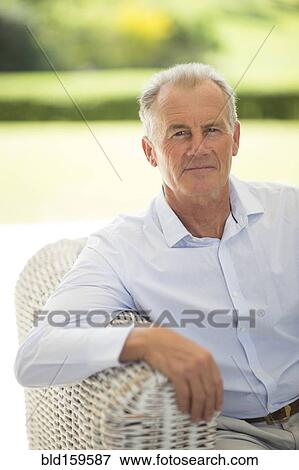 Stock Photo - Caucasian man sitting on sofa outdoors. Fotosearch