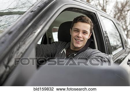 Stock Image - Caucasian man smiling in car window. Fotosearch