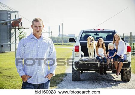 Stock Photo - Caucasian man standing near family in truck bed. Fotosearch
