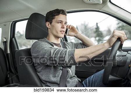 Caucasian man talking on cell phone and driving car View Large Photo Image Picture - Caucasian man talking on cell phone and driving car. Fotosearch