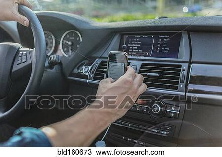 Stock Image - Caucasian man using cell phone and driving car. Fotosearch