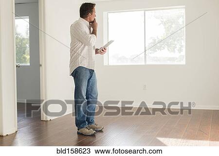 Stock Image - Caucasian man using digital tablet in empty room. Fotosearch
