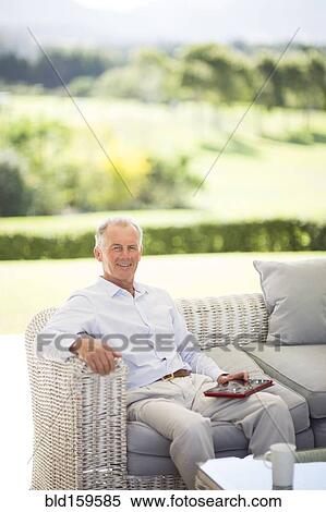 Stock Photography - Caucasian man using digital tablet on sofa outdoors. Fotosearch