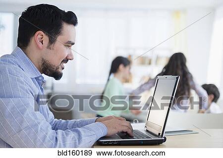 Stock Photo - Caucasian man using laptop at desk. Fotosearch