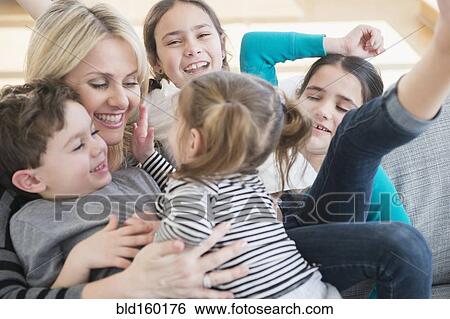 Stock Photograph - Caucasian mother and children playing on sofa. Fotosearch