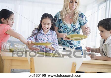Stock Photography - Caucasian mother and children setting table. Fotosearch