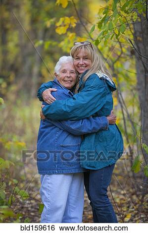 Stock Photograph - Caucasian mother and daughter hugging in forest. Fotosearch