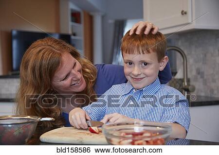 Stock Photograph - Caucasian mother and son chopping fruit in kitchen. Fotosearch