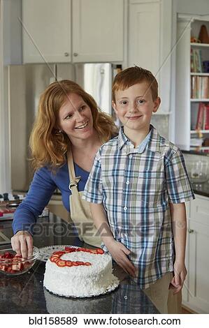 Caucasian mother and son decorating cake in kitchen View Large Photo Image Stock Photo - Caucasian mother and son decorating cake in kitchen. Fotosearch