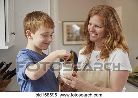 Stock Photography - Caucasian mother and son dunking cookies in milk. Fotosearch