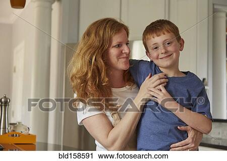 Stock Image - Caucasian mother and son smiling in kitchen. Fotosearch