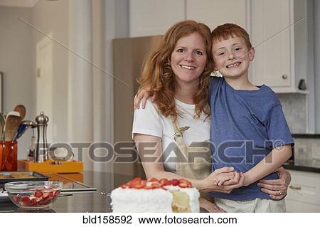 Stock Image - Caucasian mother and son smiling in kitchen. Fotosearch