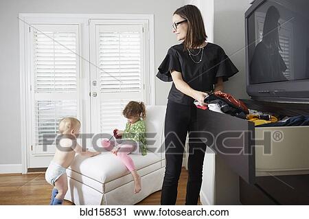 Stock Image - Caucasian mother watching children playing. Fotosearch