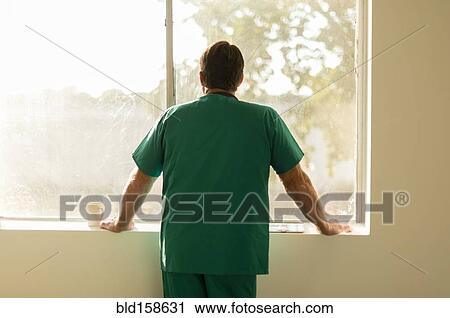 Stock Image - Caucasian nurse looking out window. Fotosearch