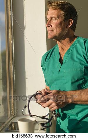 Stock Image - Caucasian nurse looking out window. Fotosearch