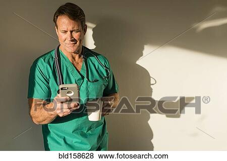 Stock Photo - Caucasian nurse using cell phone casting shadow on wall. Fotosearch