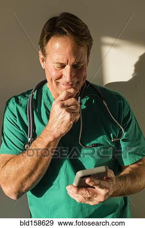 Stock Photo - Caucasian nurse using cell phone casting shadow on wall. Fotosearch