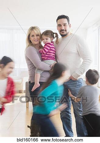 Stock Photograph - Caucasian parents busy with running children. Fotosearch
