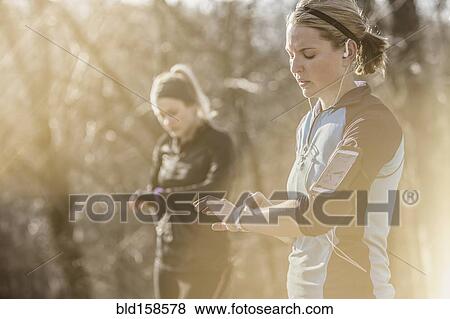 Caucasian runners checking fitness watches in forest View Large Photo Image Stock Photo - Caucasian runners checking fitness watches in forest. Fotosearch