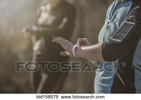 Caucasian runners checking fitness watches in forest View Large Photo Image Stock Photo - Caucasian runners checking fitness watches in forest. Fotosearch