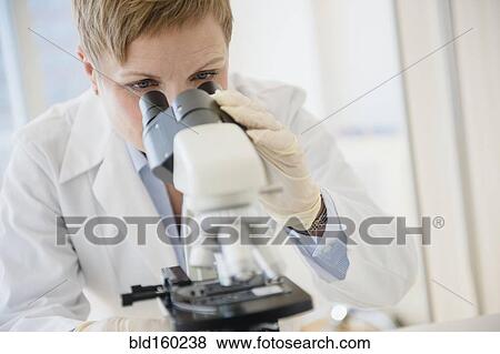 Caucasian scientist looking through microscope in lab View Large Photo Image Stock Photo - Caucasian scientist looking through microscope in lab. Fotosearch