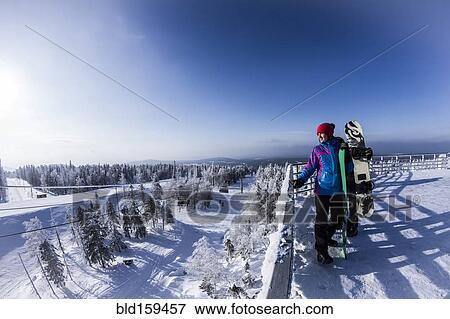 Stock Photo - Caucasian snowboarders standing on snowy mountaintop. Fotosearch