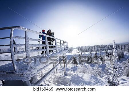 Stock Photo - Caucasian snowboarders standing on snowy platform. Fotosearch