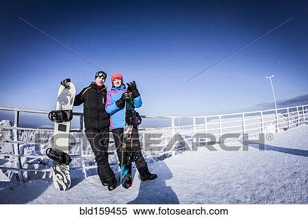 Stock Photography - Caucasian snowboarders standing on mountaintop. Fotosearch